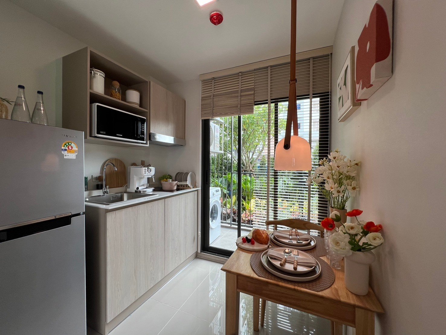 dcondo Calm: Kitchen view showing light wood cabinets, refrigerator, and small dining set.