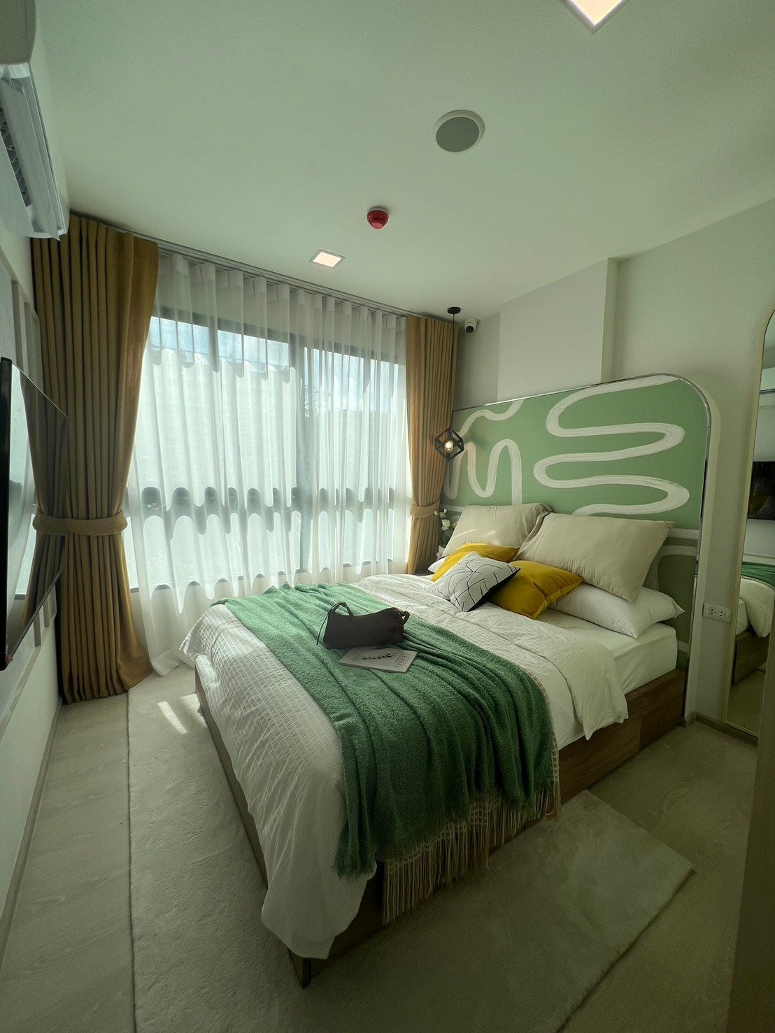dcondo Calm: Bedroom with a green and white headboard, bright window, and plush bedding.