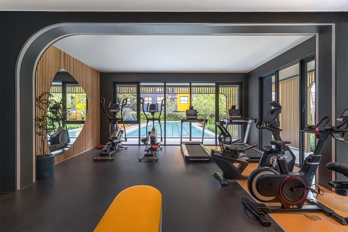 dcondo Shine Rangsit: Fitness center at dcondo Shine Rangsit with cardio equipment overlooking the pool.