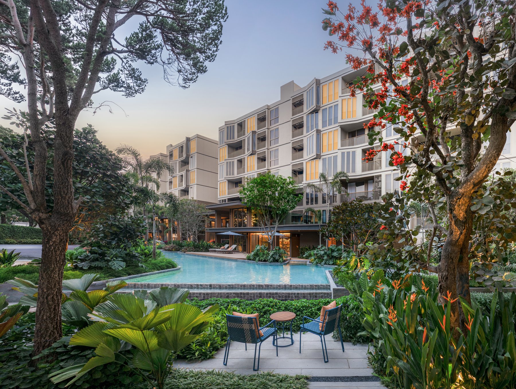 Mekin Haus: Vue extérieure de Mekin Haus et de sa piscine au crépuscule, au milieu d'un aménagement paysager luxuriant.