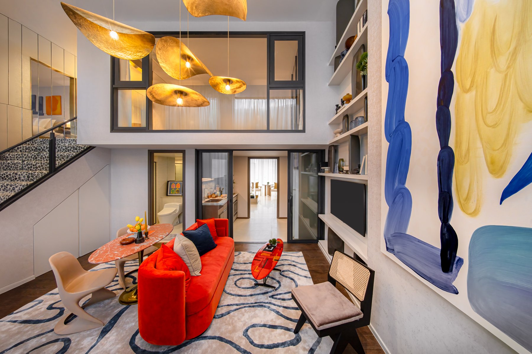 SHUSH Ratchathewi: Salon à double hauteur avec escalier et décor artistique, avec la chambre en mezzanine visible.