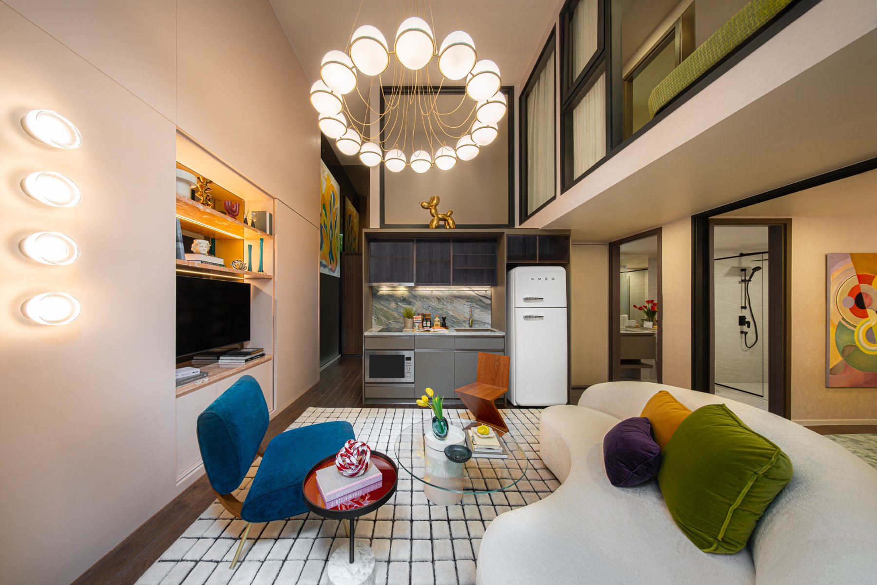 SHUSH Ratchathewi: Espace de vie avec un canapé incurvé, une cuisine compacte et un niveau supérieur en mezzanine.