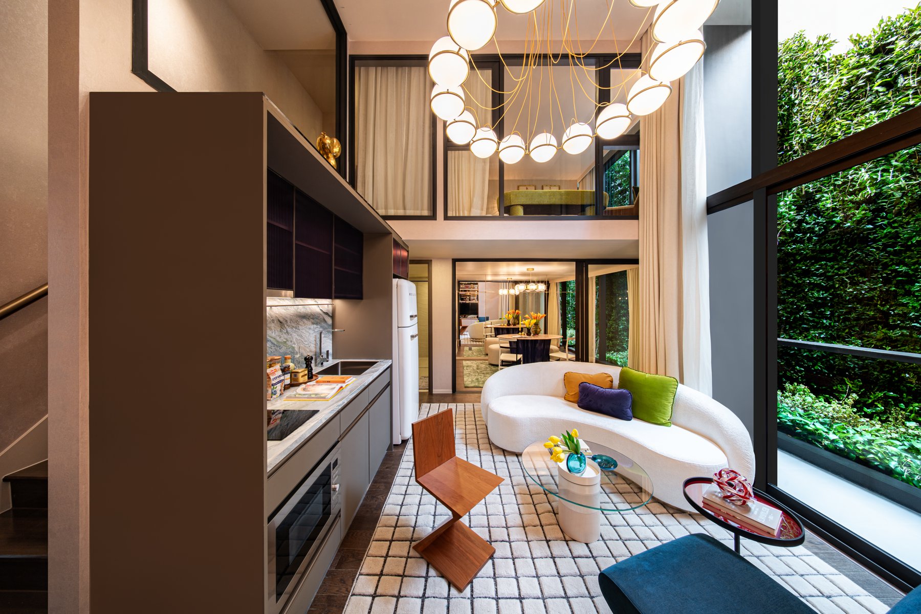 SHUSH Ratchathewi: Salon de style loft avec de hauts plafonds et une vue sur un balcon verdoyant.