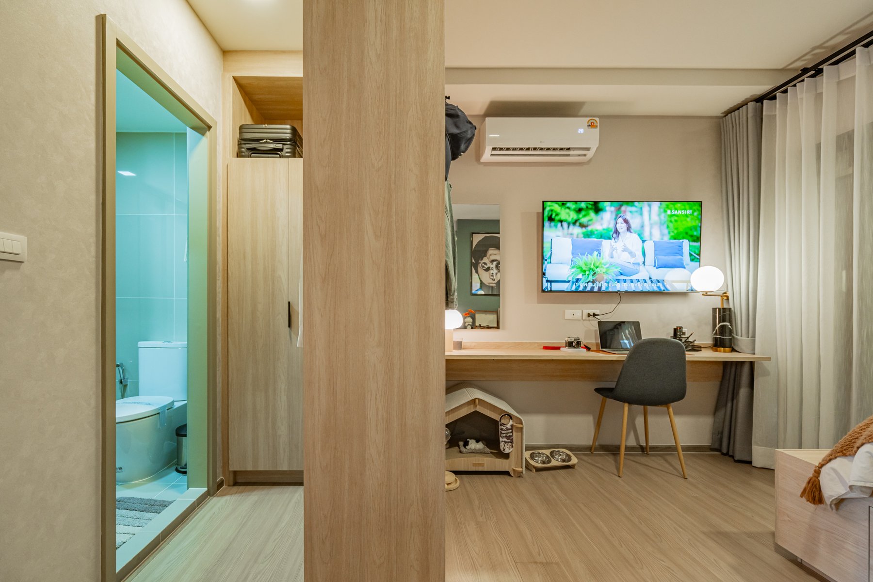 The MUVE Sukhumvit 107: Interior view of a one-bedroom unit showing a workspace and entrance to the bathroom.